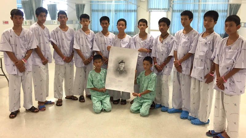 The boys stand with a picture of Saman Kunan in hospital, after they deemed healthy enough to be told of his death