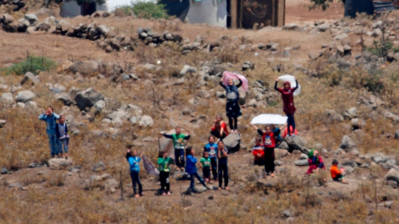 Syrian refugees hold white flags as they try to cross the border