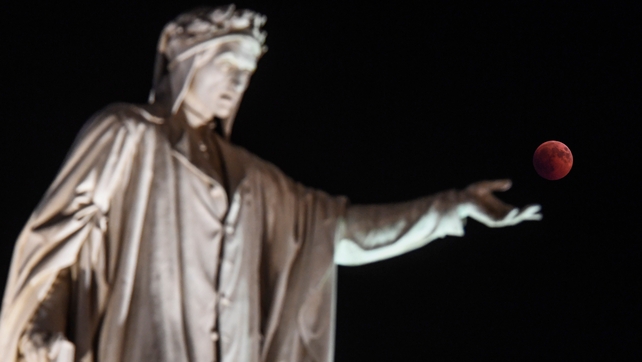 Statue of Dante Alighieri appears to reach out to the 'blood moon' in Naples