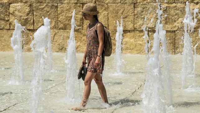 A woman cools herself in a fountain near the Ara Pacis monument in central Rome