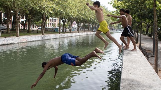 People jump into the Lis river to cool off in Leiria, central Portugal