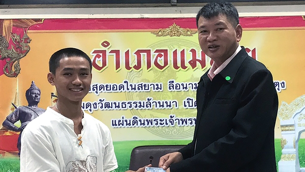A member of the Wild Boar soccer team Adul Sam-on (L) receives his Thai citizen ID card from Mae Sai District Chief Somsak Kanakham
