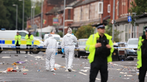 Police and forensic investigators at the scene in Moss Side