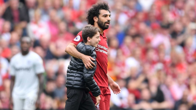 A young fan embraces Mo Salah during Liverpool's clash with West Ham at Anfield