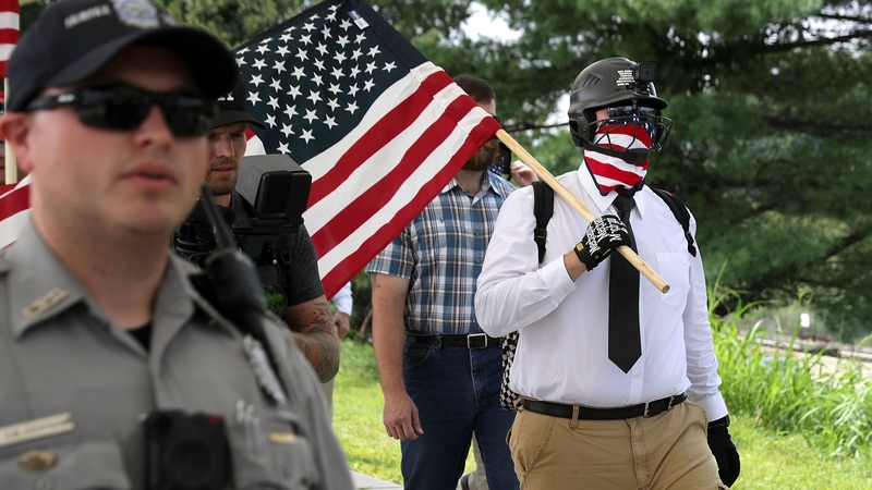 Police officers escort white supremacists as they walk to a train station to travel to the White House for rally