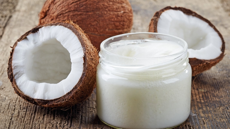 Fresh coconuts and a jar of coconut oil on a wooden table