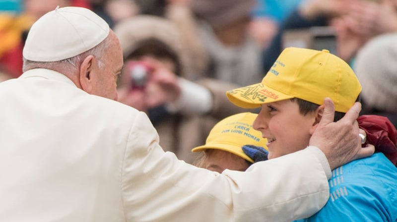 Pope Francis greets a child as he arrives for his weekly general audience the day after the Parkland school shooting