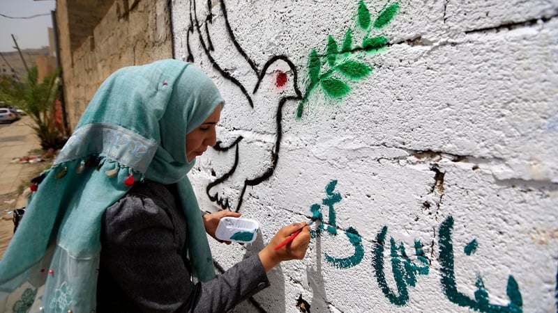 A Yemeni artist paints pro-peace graffiti on a wall in the capital Sanaa