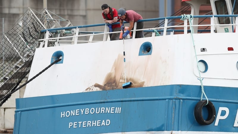 Members of the crew clean marks from the stern of the Honeybourne III, following clashes with French fishermen