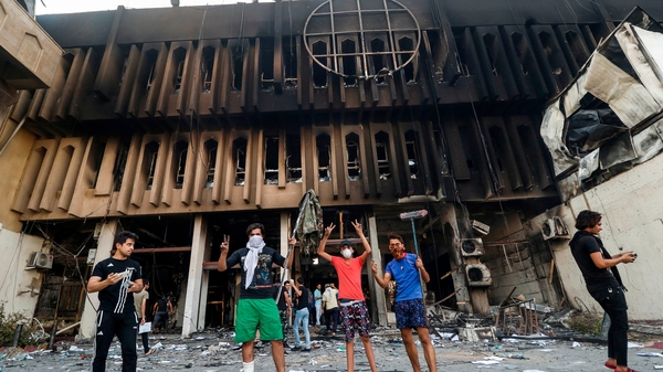 Protesters gather at the burnt-down local government headquarters in Basra