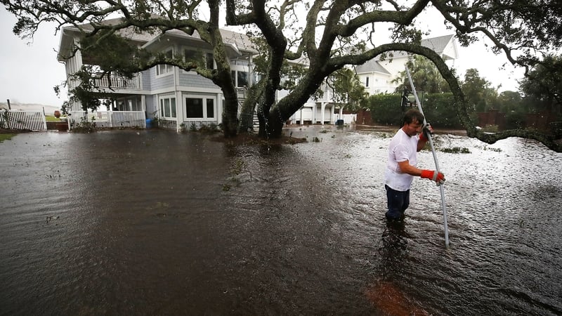 A man searches for a drain in the yard of his flooded waterfront home in Wilmington, North Carolina