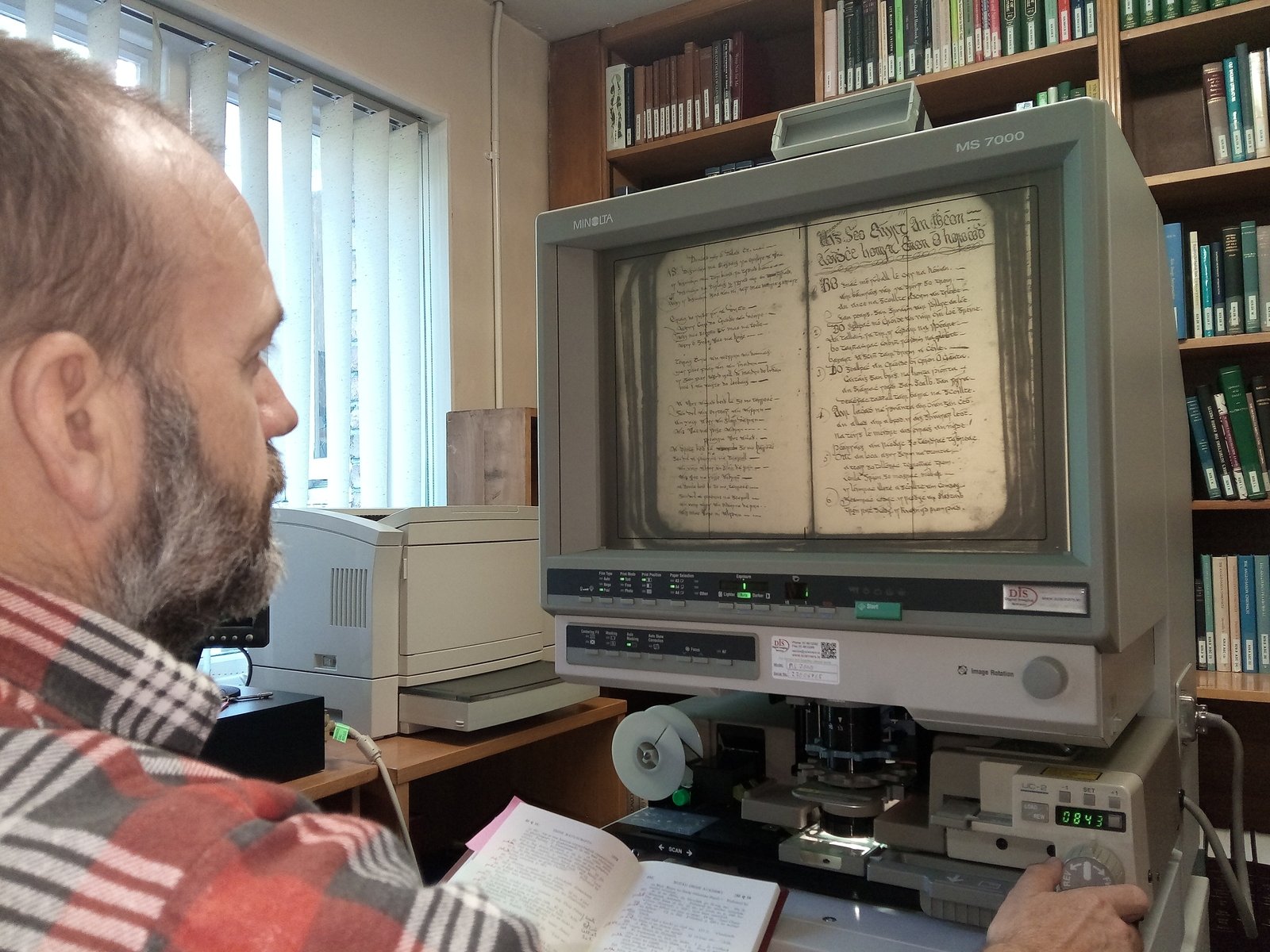 Professor Brian Ó Curnáin studying Éamann Ó hOrchaidh's manuscript on microfilm