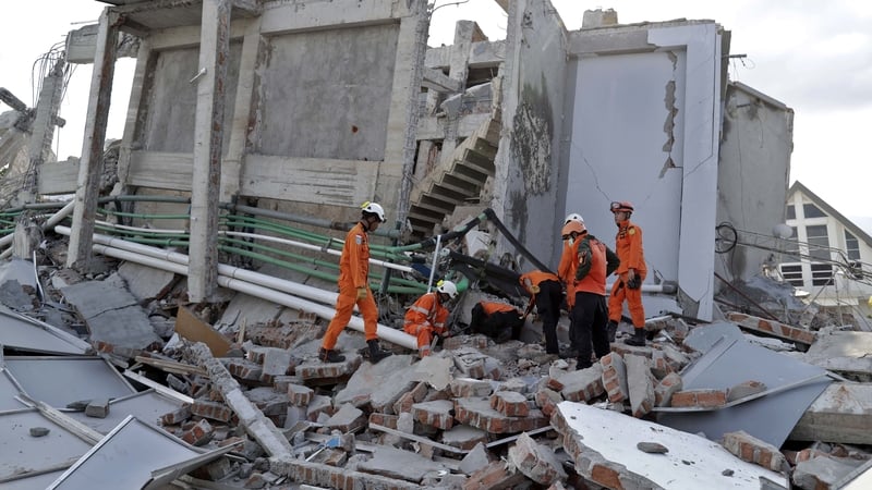 Rescuers search for survivors at the collapsed Roa Roa hotel building in Palu