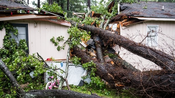 A fallen tree rests on a house after remnants of Hurricane Michael passed through