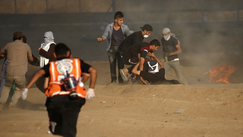 Palestinians medics help a protester near the border