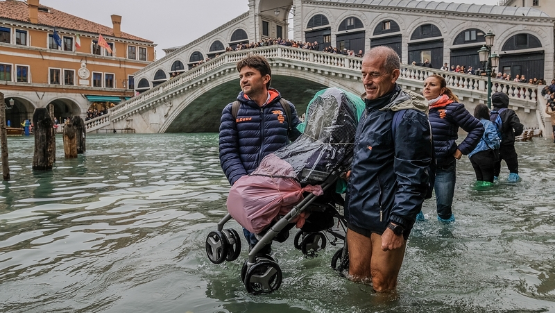 People carry a buggy over the flood waters in Venice