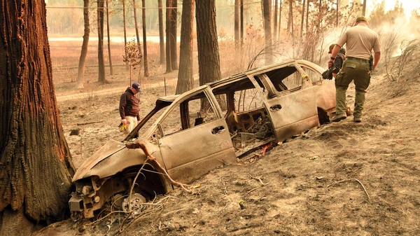 Police examine the burned wreck of car near where the remains of a person were found