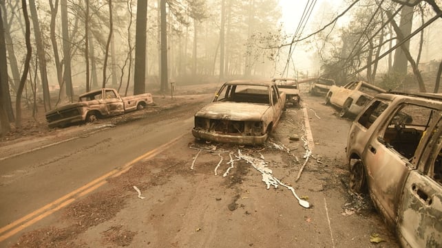 A fallen power line is seen on top of burnt out vehicles on the side of the road in Paradise