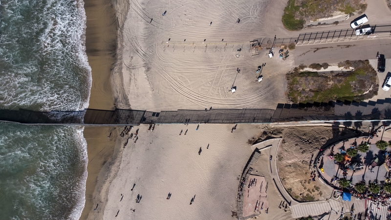 Groups of migrants have been gathering on the beach at the border fence that separates Mexico from California