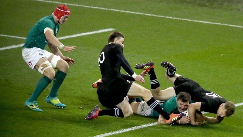 Jacob Stockdale crosses the try line against New Zealand despite the efforts of Damian McKenzie and Beauden Barrett
