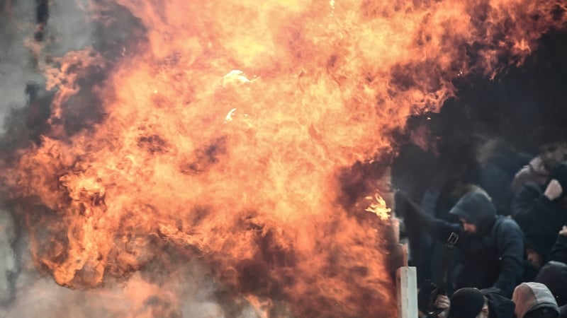 Ajax fans try to shield themselves from flames during clashes with Greek riot police prior to the start of the Champions League football match against AEK Athens