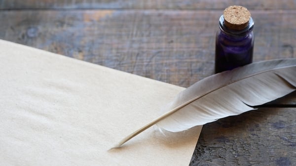 Closeup of scroll and quill near ink-pot on wooden table