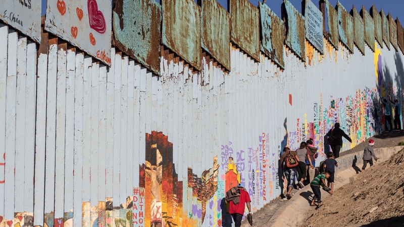 Migrants from Honduras try to walk along the US-Mexico border fence in Playas de Tijuana, Baja California State, Mexico