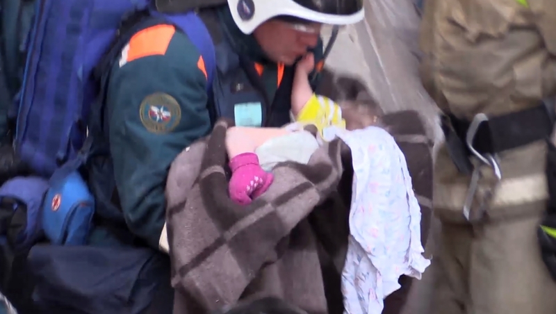 Rescue workers rush a baby from the site of the apartment block collapse