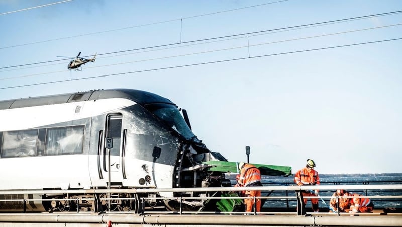 Men work at the accident site next to a passenger train standing on the rails in Nyberg, Denmark
