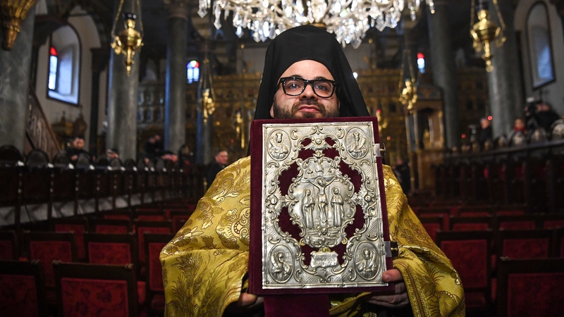 An Orthodox cleric holds the Bible before the start of a ceremony for the signing of the 'Tomos' decree