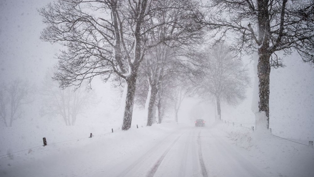 A car drives through a snowy road in Warngau, southern Germany