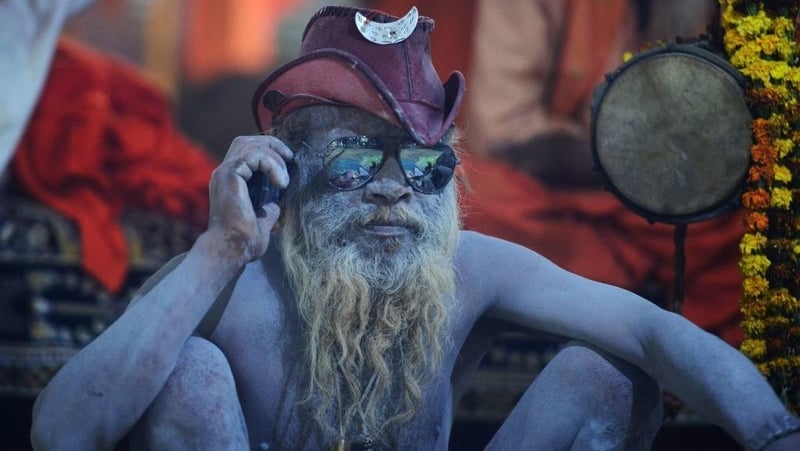 Hindu holy man takes a call on his mobile phone at the Kumbh Mela