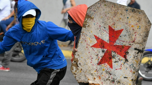 <p>An opposition protester uses a makeshift shield as they clash with security forces</p>