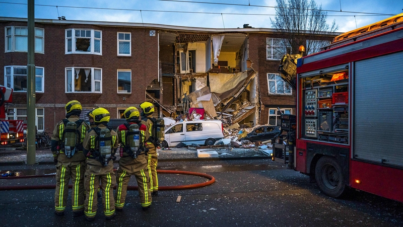Firefighters stand in front of the building following the explosion