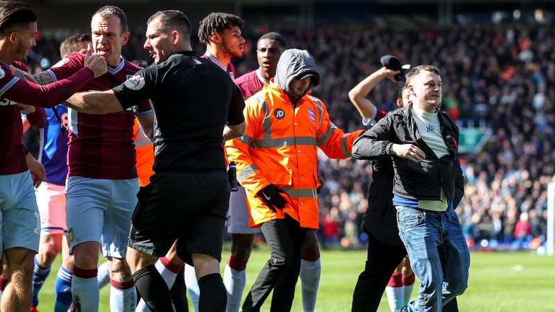 A fan is escorted off the pitch after attacking Jack Grealish.