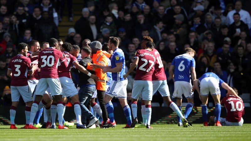 Paul Mitchell (C, black jacket) is restrained after attacking Aston Villa's Jack Grealish on the pitch (right)