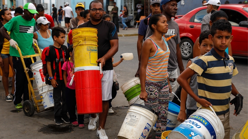 People queue for water in Caracas after a power outage affected supply of several services