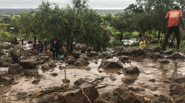 Residents of Chiluvi, in central Mozambique, walk along a flooded and muddy street after Cyclone Idai and floods hit the region