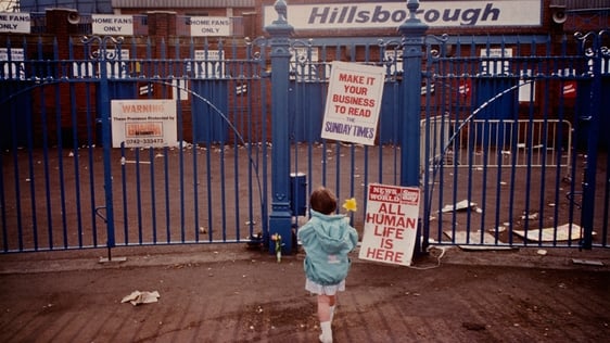 A young girl lays a single flower outside the entrance to Hillsborough Stadium after the stampede w…