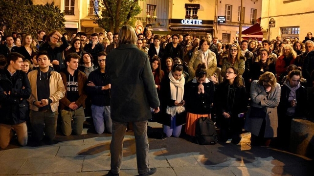 People pray and look on as firefighters douse flames to extinguish the fire