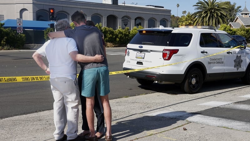 People hug next to police tape across the street from the Chabad of Poway Synagogue