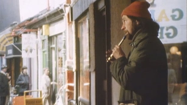 Justin O'Mahony in a red wool hat playing the tin whistle