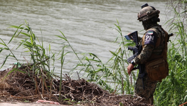 Mexican police patrol the area where the bodies of Oscar Ramirez and his daughter were found