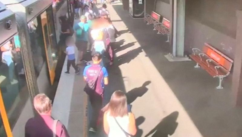 The young boy fell as he tried to board the train with his mother