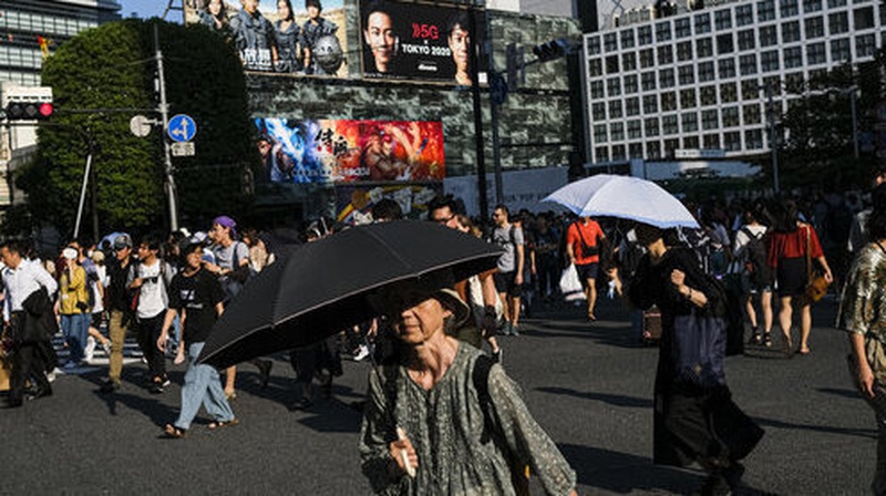 People hold umbrellas at the Shibuya crossing in Tokyo to protect them from the summer heat