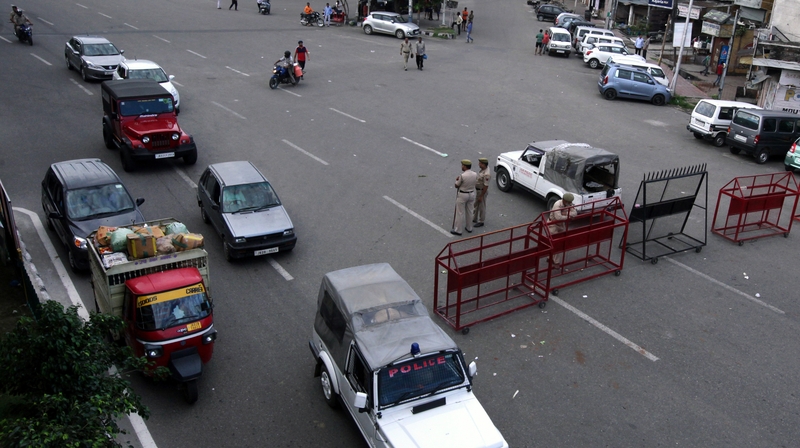 Vehicles move past a police checkpoint as tensions rise in Kashmir