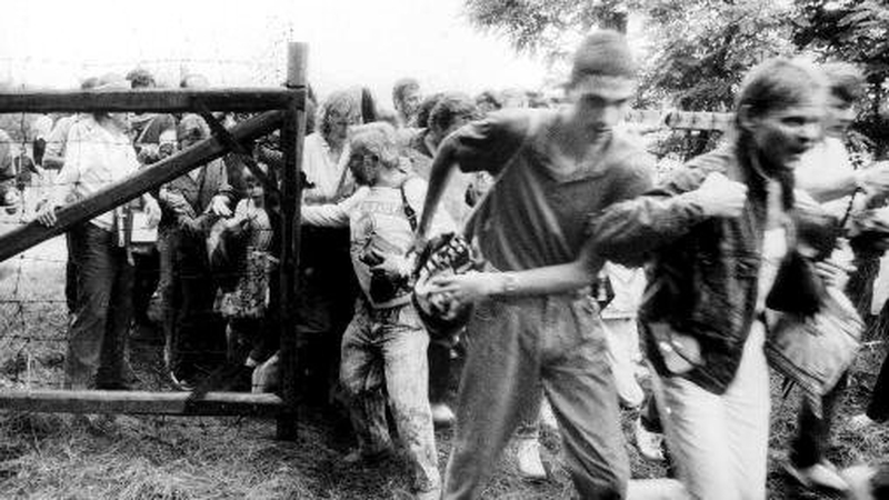 East German citizens break through a gate of the fence separating Hungary and Austria on the border between the two countries near Sopron during the Pan-European Picnic on 19 August 1989