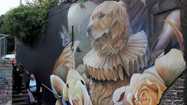 A woman looks over a mural titled 'Ned The Dog' by Curtis Hylton