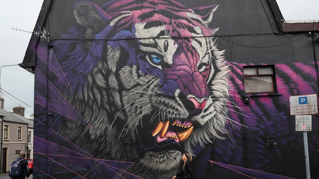 People pass a mural titled 'Electric Fury' by Sonny