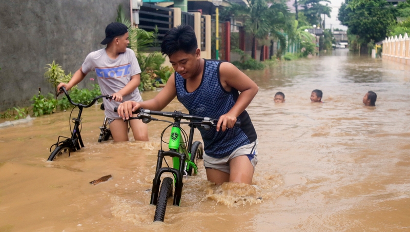 People navigate flood waters in Bacarra, Ilocos Norte province, Philippines last month